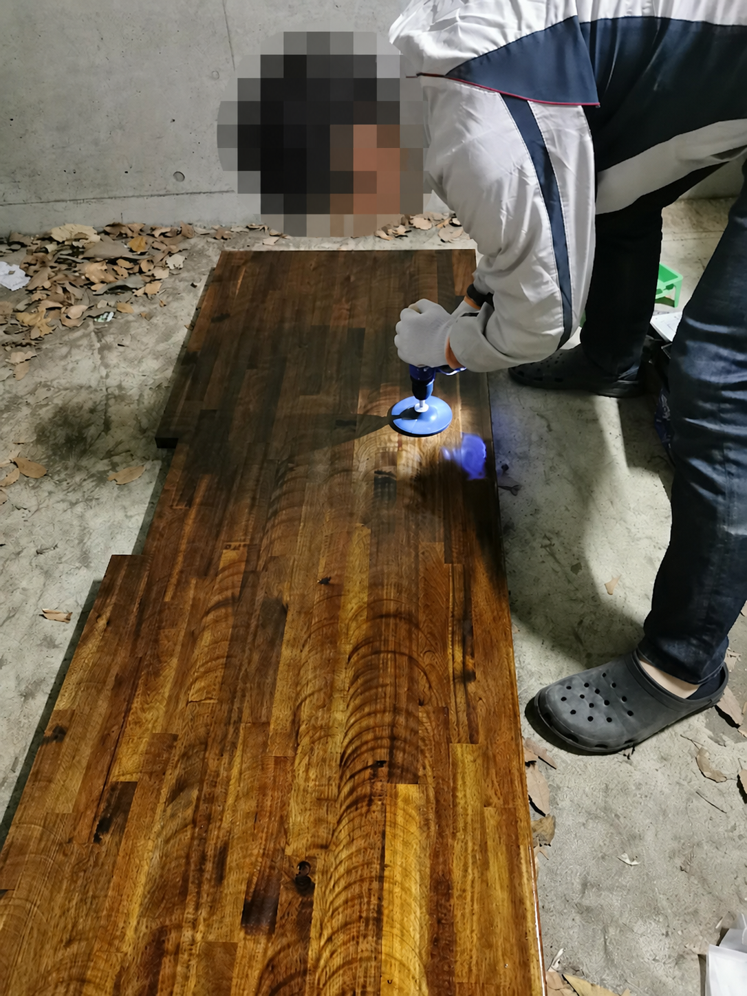 アカシア天板を電動工具で研磨する作業。人物の頭全体をモザイク処理